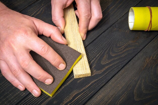 De meester poetst een houten plank met een schuurmiddel