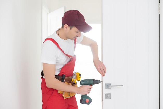 De meesterwerker installeert een deurslot in de voordeur, metalen deuren met een polymeercoating.