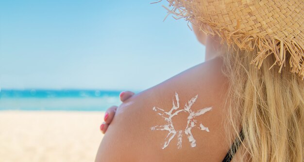 De meisjes op het strand dragen zonnebrandcrème op hun huid