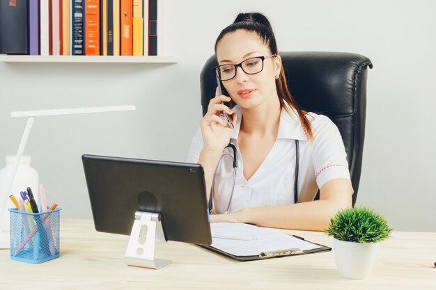 De meisjesdokter praat aan de telefoon vanuit haar kantoor