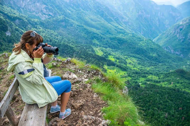 De meisjesfotograaf op de bank maakt foto's van prachtige uitzichten vanaf de top van de berg.