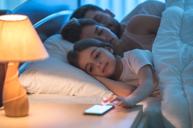 De meisjestelefoon dichtbij de slapende ouders. nachttijd