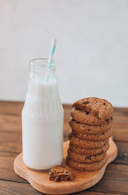 De melk die in een fles wordt gegoten, staat op tafel naast een stapel koekjes. ontbijt met melk en koekjes