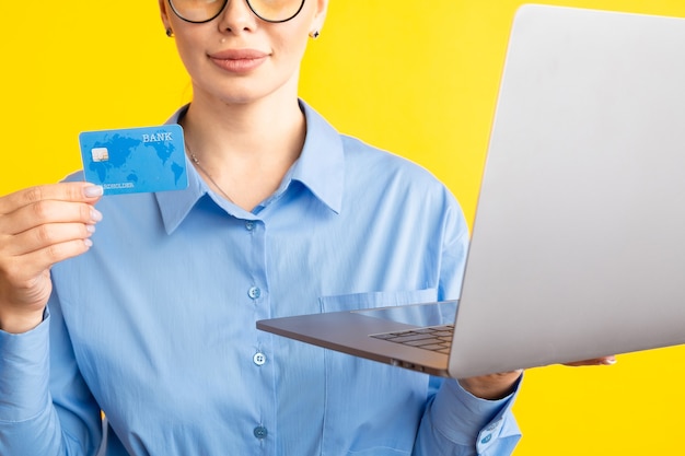 De mening van de close-up van vrouw in de blauwe laptop en de creditcard van de shurtholding op geel