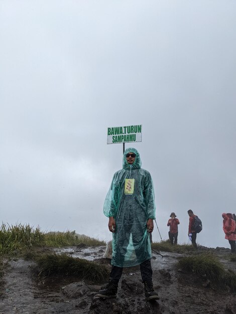 De mens bereikt de top van de berg op een regenachtige dag met mistige vibes