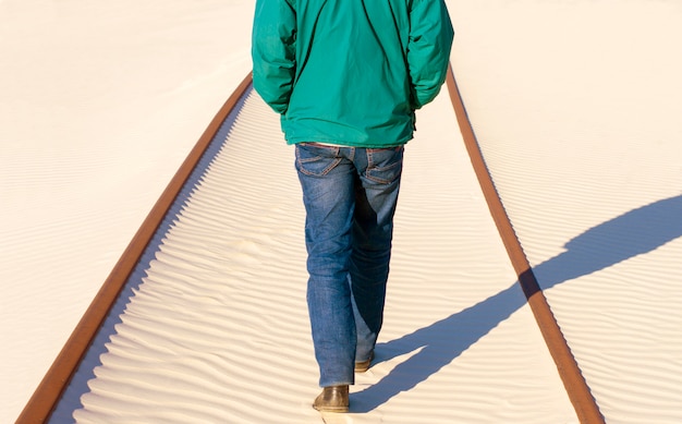 De mens bevindt zich op de spoorweg in het zand