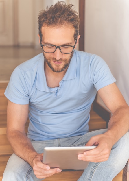 De mens gebruikt een digitale tablet en glimlacht