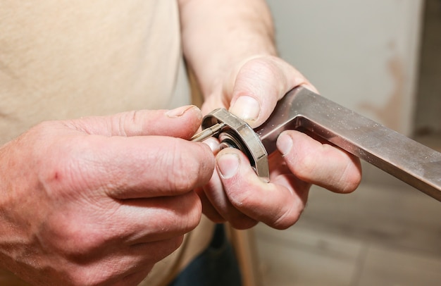 Foto de mens installeert de deurklink. reparatie werkt. onderhoud in het appartement.