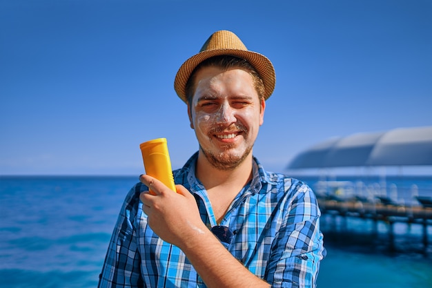 De mens is op vakantie en besmeurd met sunblock, en houdt het in zijn hand.