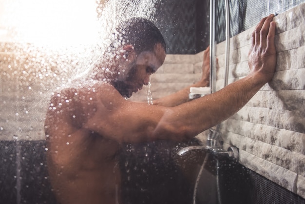 Foto de mens leunt op de muur terwijl het nemen van douche in badkamers.