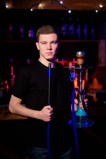 De mens maakt waterpijp. Moderne waterpijp met kokoshoutskool om te ontspannen en shisha-rook.