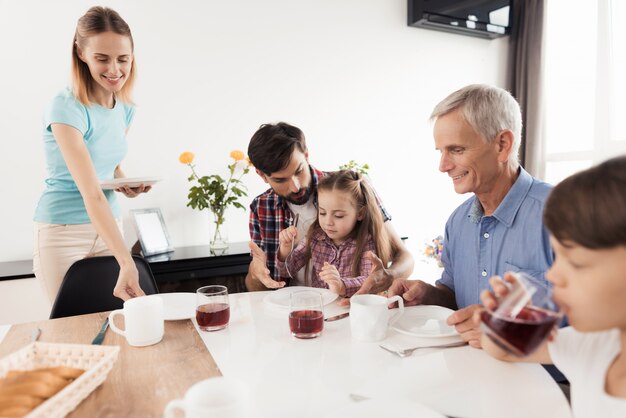 De mens onderwijst meisje om vorkjongen te gebruiken drinkt sap van een glas