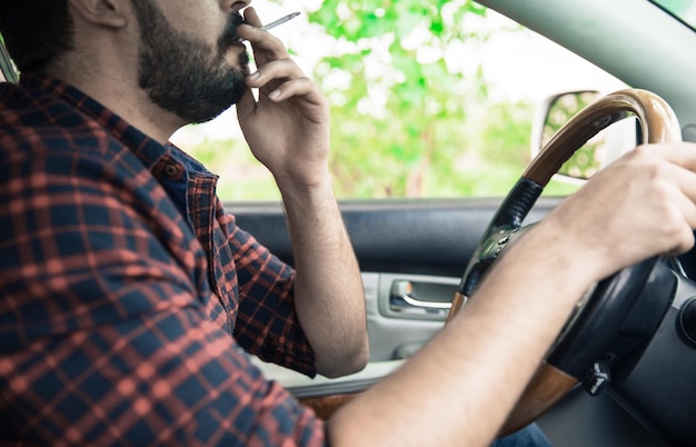 De mens rookt sigaretten en rijdt in de auto