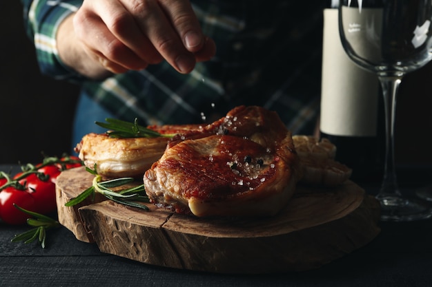 De mens strooit zout op steaks. Samenstelling met gegrilde gerechten