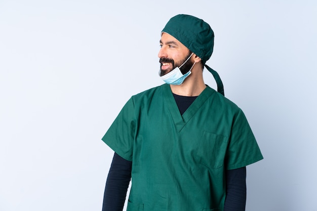 De mens van de chirurg in groen uniform over muur die kant kijkt