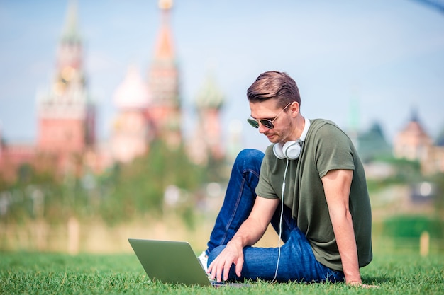 De mens werkt door laptop terwijl het ontspannen in het park