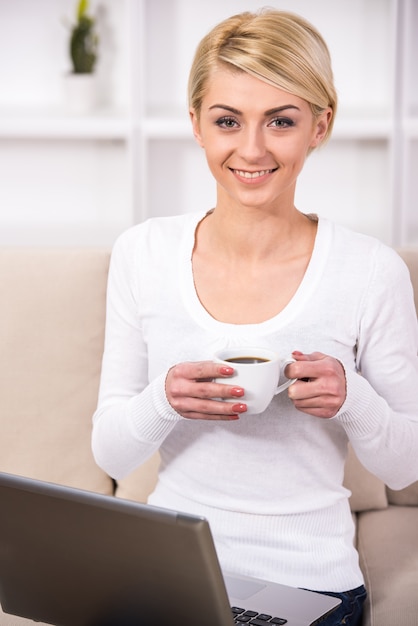 De mens werkt met laptop op kantoor en drinkt koffie.