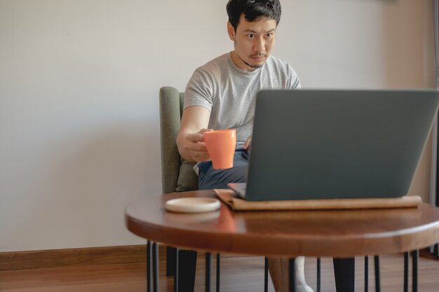 De mens werkt met zijn laptop en drinkt koffie.