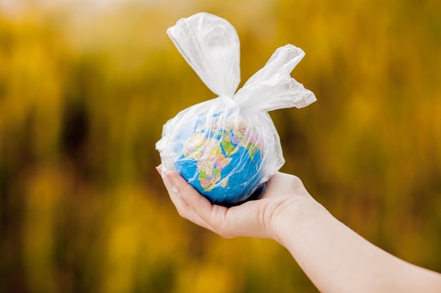 Foto de menselijke hand houdt de planeet aarde in een plastic zak het concept van vervuiling door plastic puin globale opwarming als gevolg van het broeikaseffect