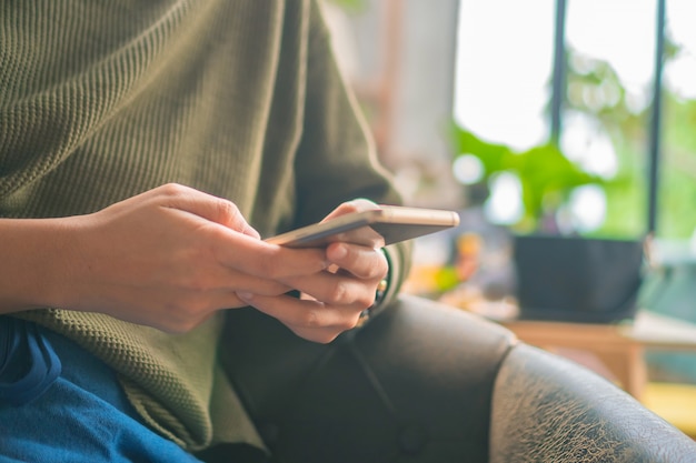 De mensen overhandigen het gebruiken van smartphone met de winkelachtergrond van de onduidelijk beeldkoffie.