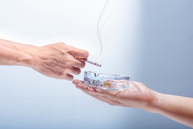 De mensenhand geeft een transparante asbak aan roker