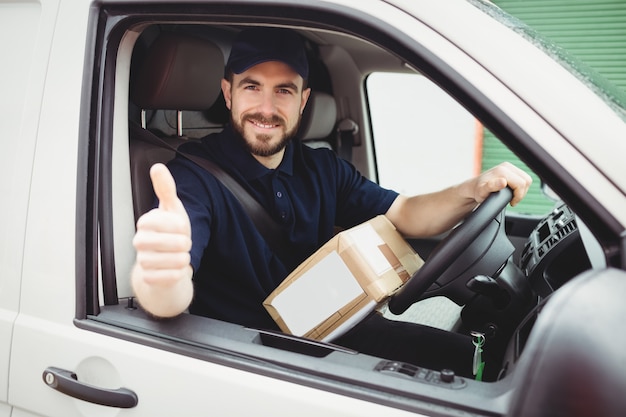 De mensenzitting van de levering in zijn bestelwagen met omhoog duimen