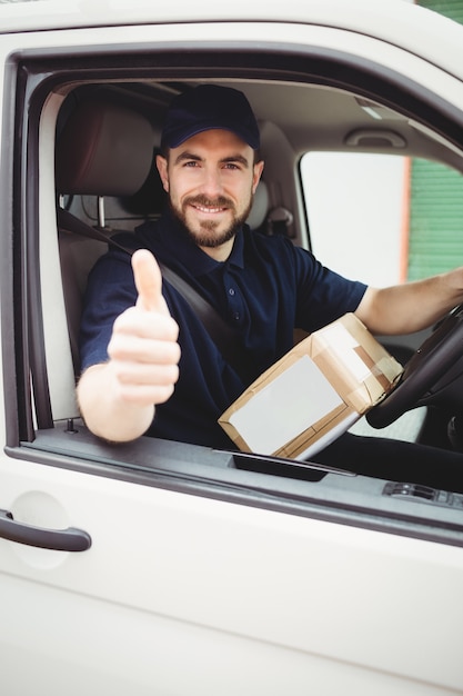 De mensenzitting van de levering in zijn bestelwagen met omhoog duimen