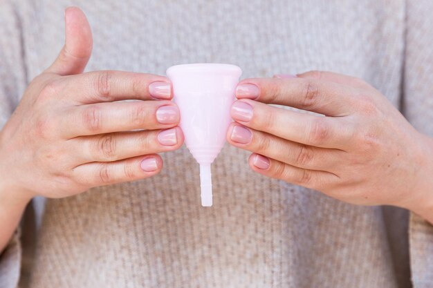 De menstruatiecup wordt vastgehouden door vrouwenhanden Selectieve focus