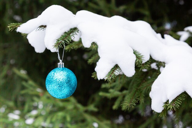 De met sneeuw bedekte dennentak is versierd met kerstballen