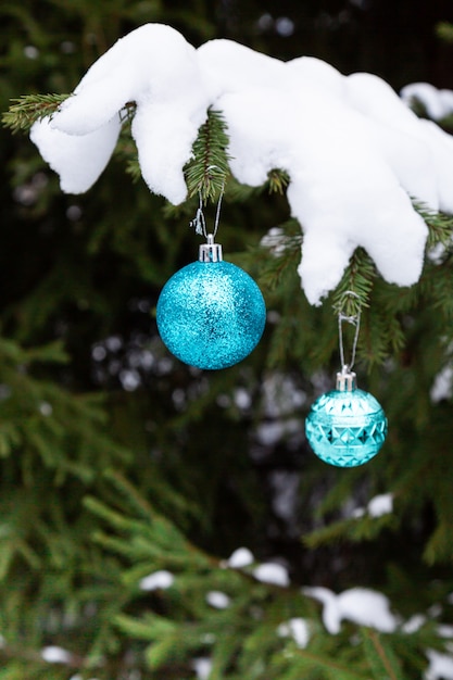 De met sneeuw bedekte dennentak is versierd met kerstballen