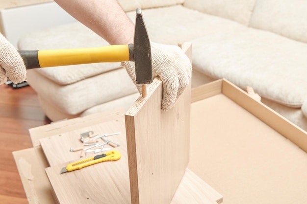 De meubelmonteur maakt twee delen van de meubelplank vast. Montageproces voor kastmeubels DIY Assembleren Close-up: