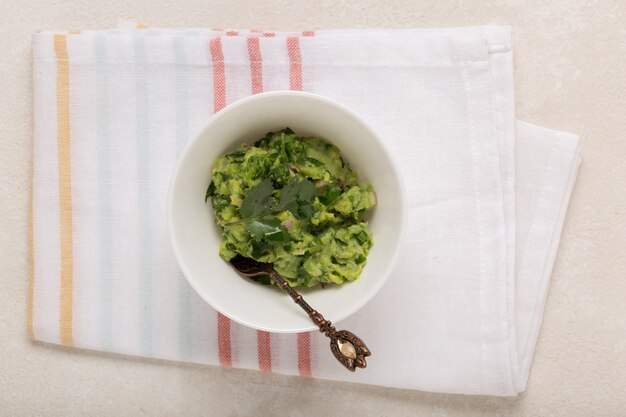 De Mexicaanse guacamole saus in een witte kom op een concrete achtergrond, hoogste mening, sluit omhoog