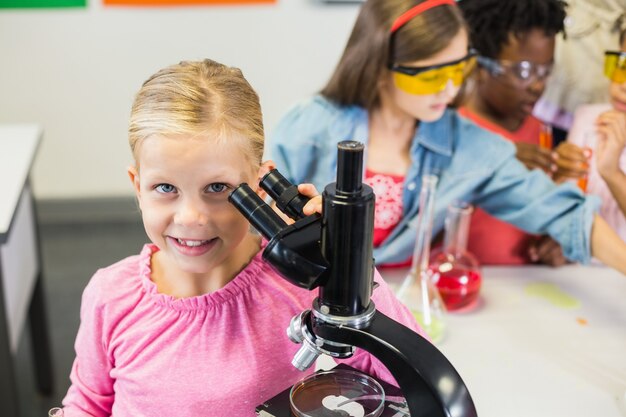 De microscoop van de schoolmeisjeholding in laboratorium