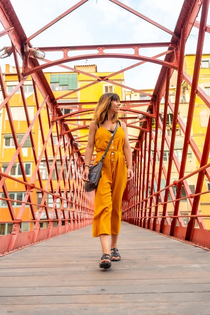 De middeleeuwse stad girona, een jonge oranje toerist op de beroemde rode brug pont de les peixateries velles, costa brava van catalonië