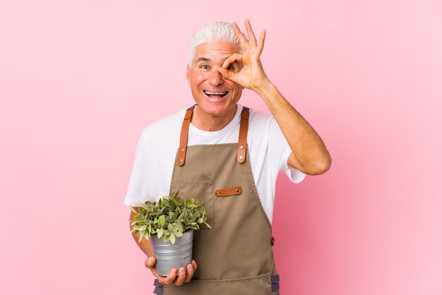 De midden oude tuinmanmens isoleerde opgewekt het houden van ok gebaar op oog.