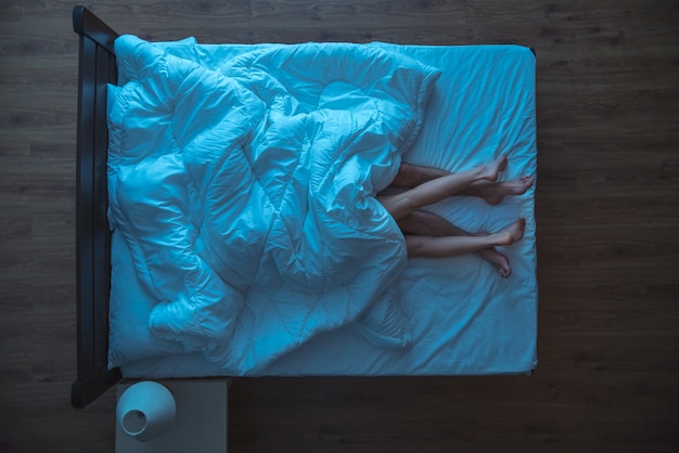 De minnaars lagen onder dekbed op het bed. avond nacht tijd. uitzicht van boven