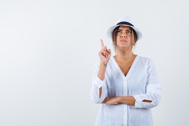 De modevrouw denkt door met haar wijsvinger op een witte achtergrond te wijzen