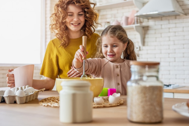 De moeder en de dochter bereiden samen een cake in de keuken voor