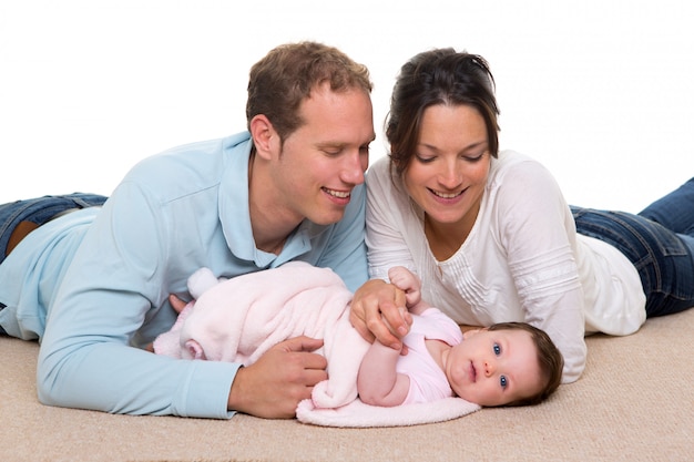 De moeder en de vader gelukkige familie die van de baby op tapijt liggen