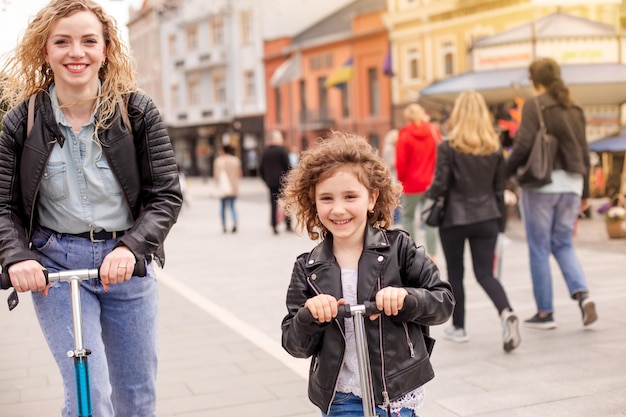 De moeder en dochter hebben veel plezier op scooters