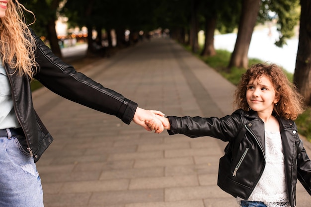 Foto de moeder en het kleine meisje lopen hand in hand door de stad