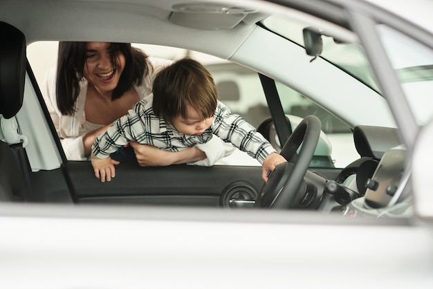 De moeder kiest een auto waarin het handig is om haar zoontje te vervoeren.