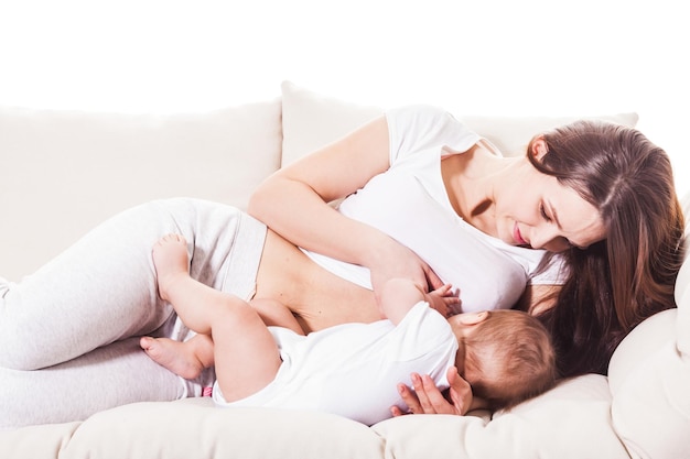 De moeder ligt op de bank en staat op het punt haar baby borstvoeding te geven