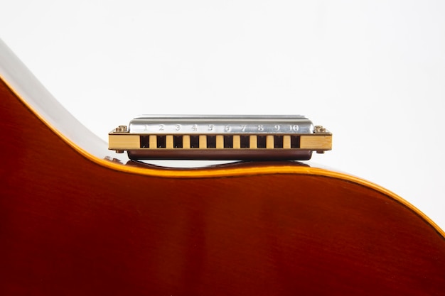 De mondharmonica rust op de body van een klassieke gitaar. Klassiek muzikaal blaasinstrument.