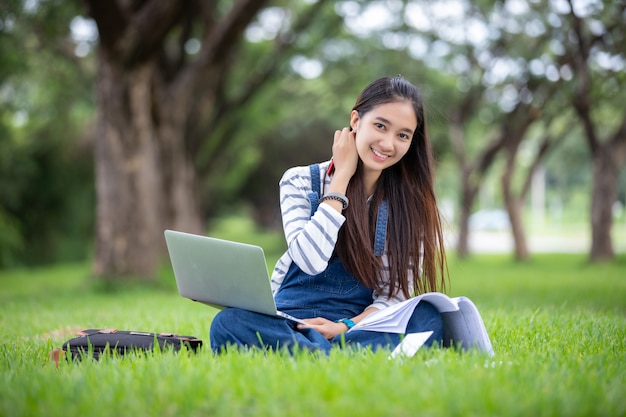 De mooie Aziatische boeken van de studentenholding en het glimlachen en het leren en onderwijs op park in de zomer voor ontspannen tijd