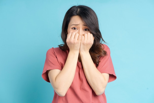 De mooie Aziatische vrouw hield haar mond met beide handen kegel met een bang gezicht