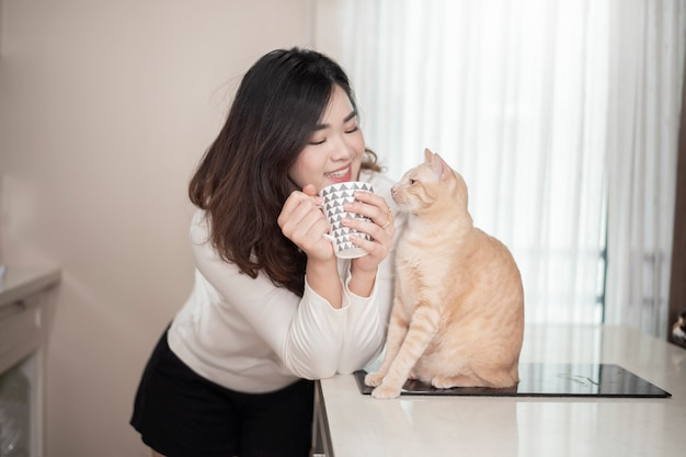 De mooie Aziatische vrouw van de kattenminnaar speelt met kat in haar ruimte