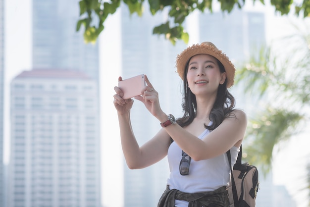 De mooie Aziatische vrouw van de solooerist geniet van nemend foto door slimme telefoon bij sightseeingsvlek.