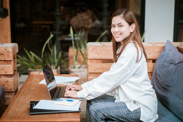De mooie bedrijfsvrouw werkt met haar laptop computer in koffiewinkel