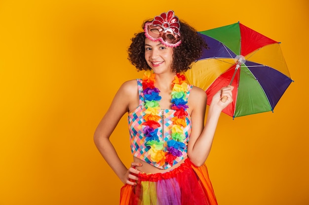 De mooie Braziliaanse vrouw kleedde zich in Carnaval-kleding die het kleurrijke paraplu glimlachen draagt